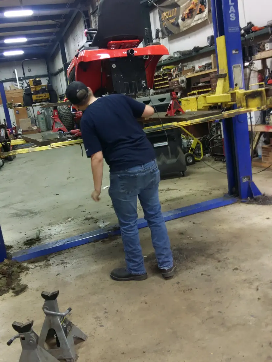 Technician servicing a lawn tractor on a shop lift